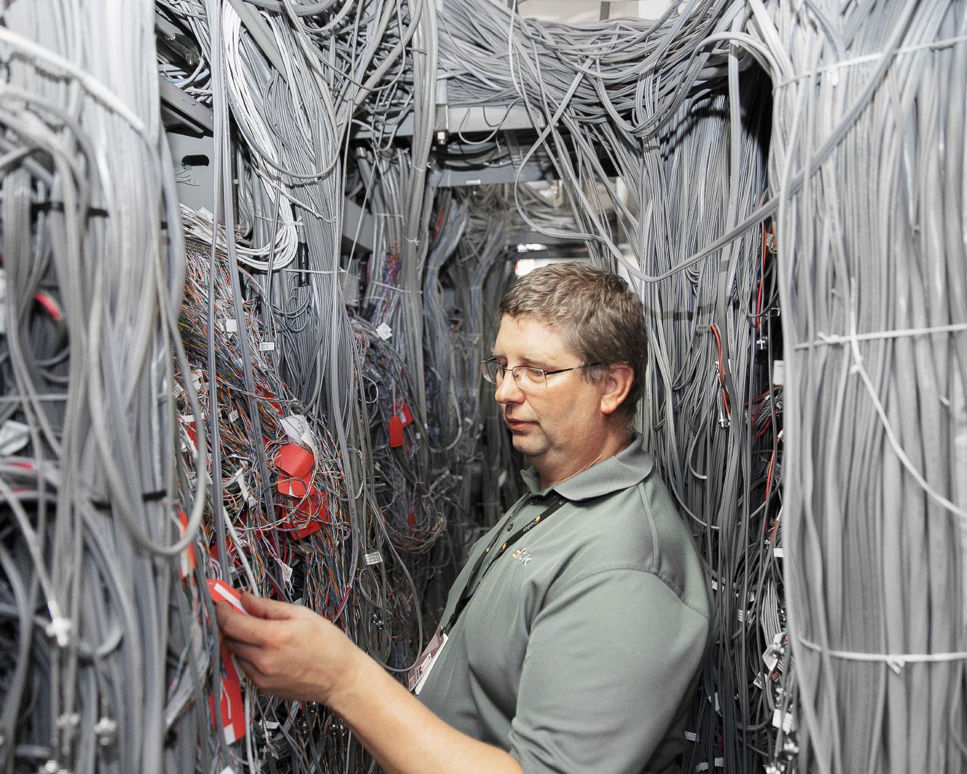 A technician working in a room with 100's of ethernet cables